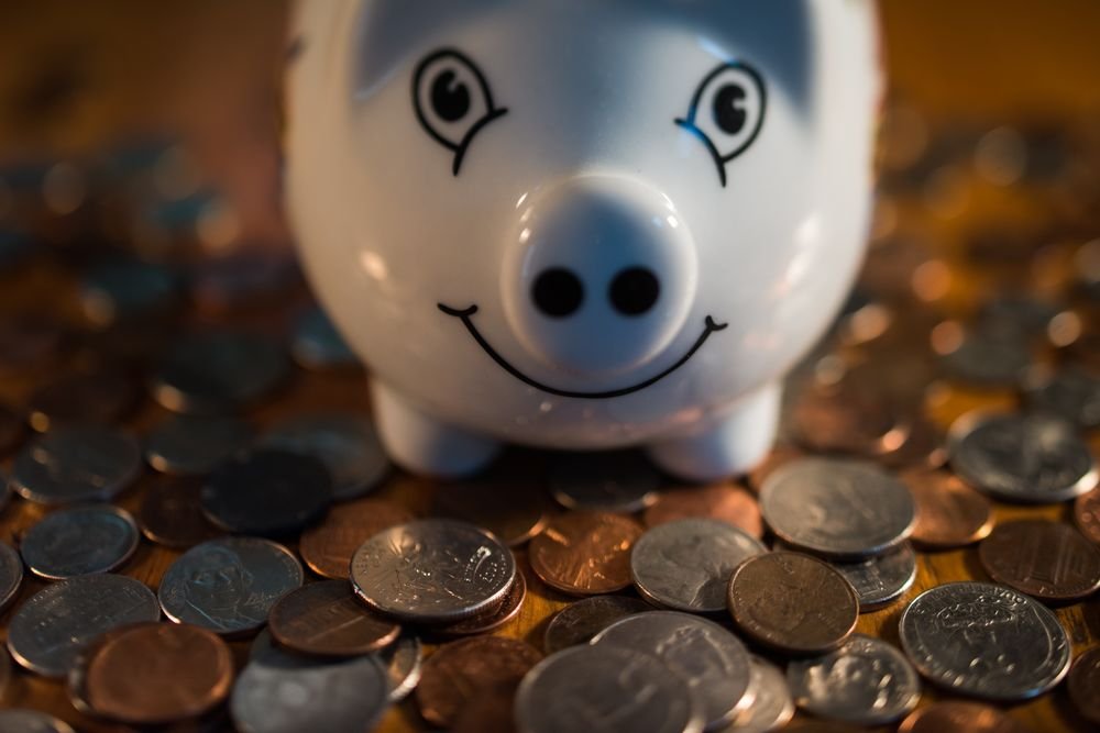 A smiling piggybank is surrounded by coins