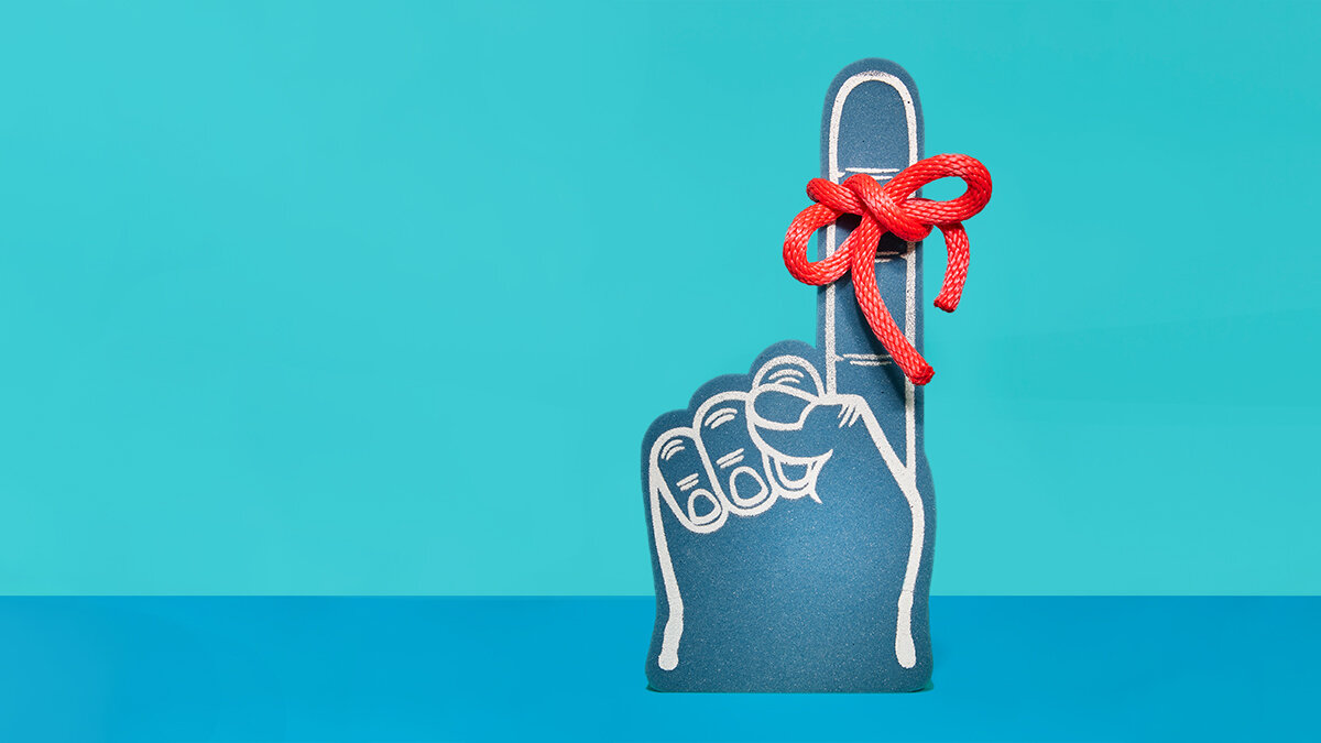 A blue foam finger sports a red string tied in a bow as a reminder