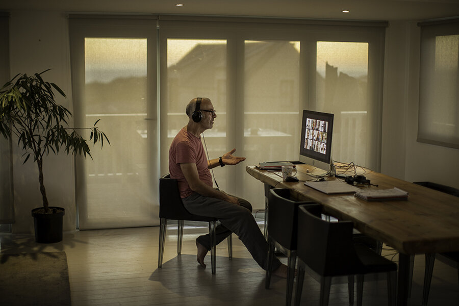 A remote worker sits in front of his computer in his kitchen during a virtual meeting