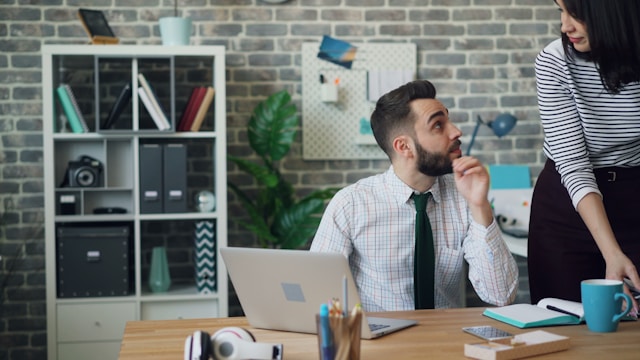 Sitting man with laptop speaking to woman