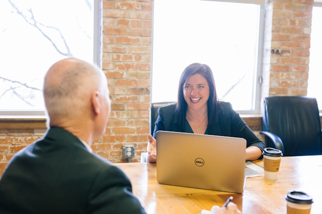 Businesswoman in front of laptop smiling at a businessman Businesswoman in front of laptop smiling at a businessman