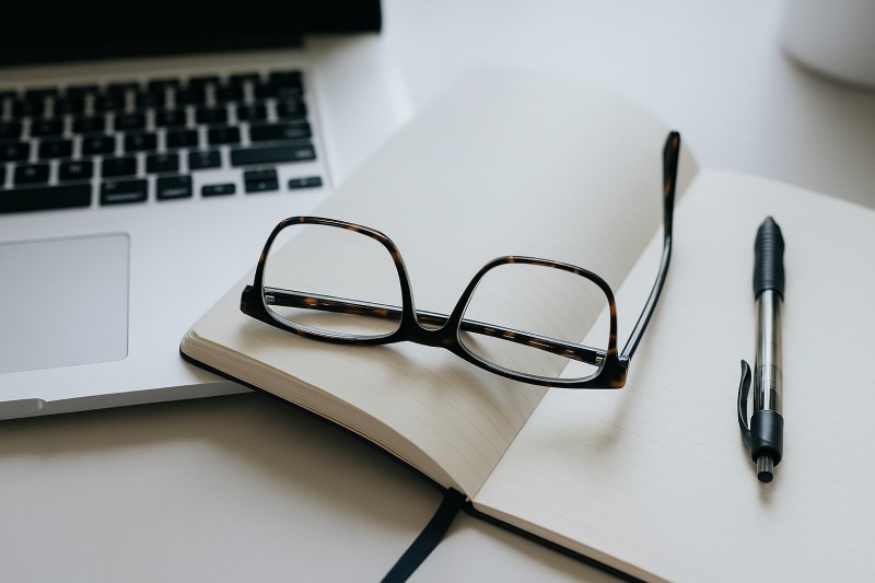 Laptop, glasses, notebook, and pen